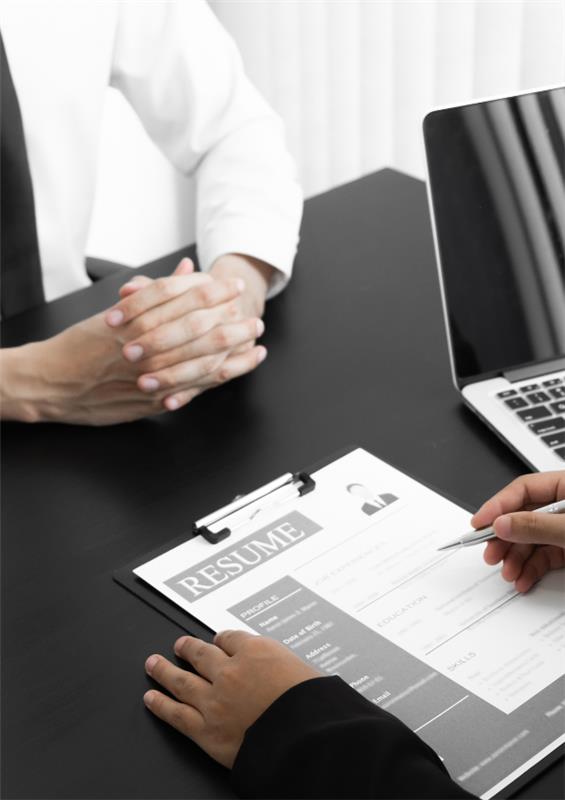 2 people having a discussion over a resume on a desk